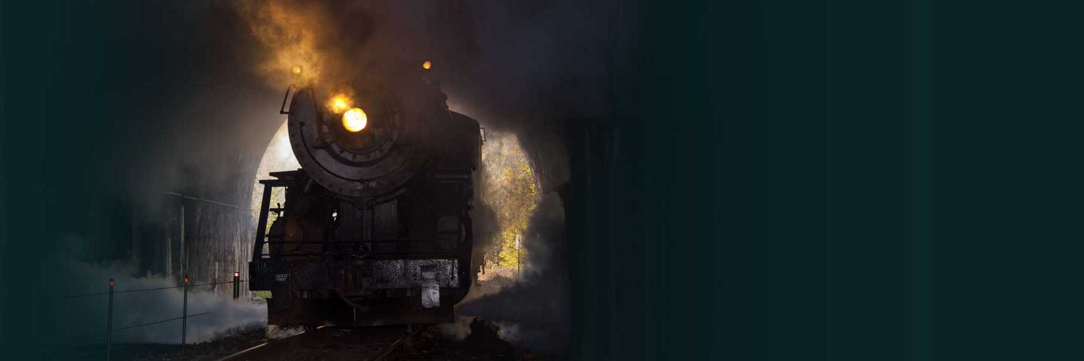 Vintage steam locomotive emitting smoke against a dark background